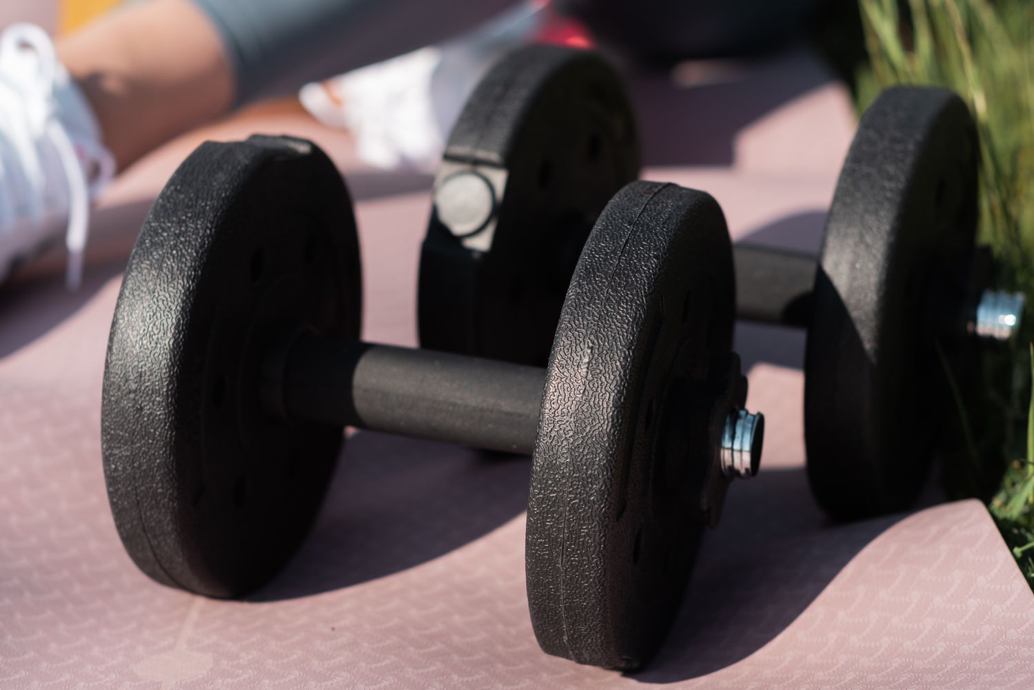 A pair of dumbbells resting on a pink exercise mat